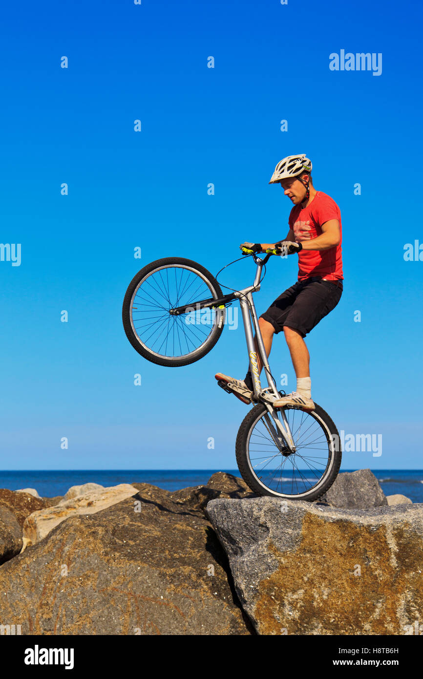 Mountainbiker, springen über Felsen auf der Hafenmauer in Staithes, North Yorkshire Stockfoto