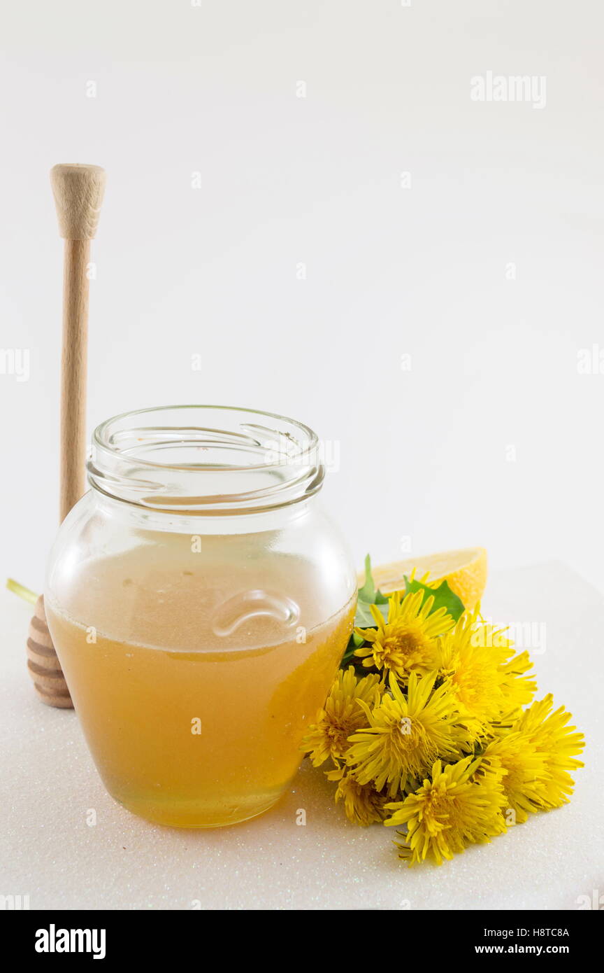 Glas mit Honig und gelbe Löwenzahn auf glänzendem Hintergrund Stockfoto