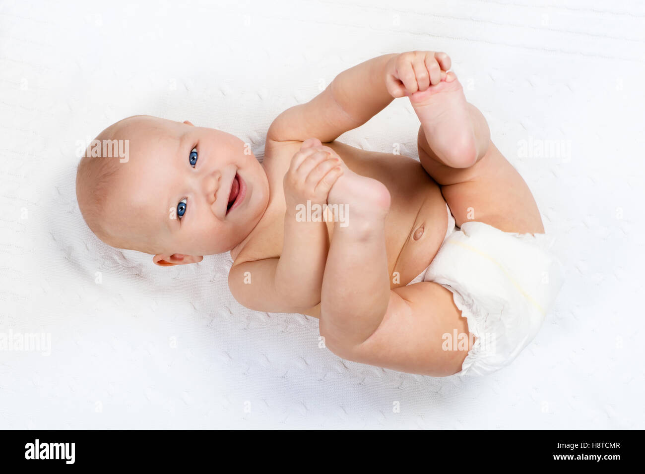 Lustige kleine Baby tragen eine Windel auf einer weißen gestrickte Decke in  einem sonnigen Kindergarten spielen. Kind nach dem Baden oder Duschen  Stockfotografie - Alamy