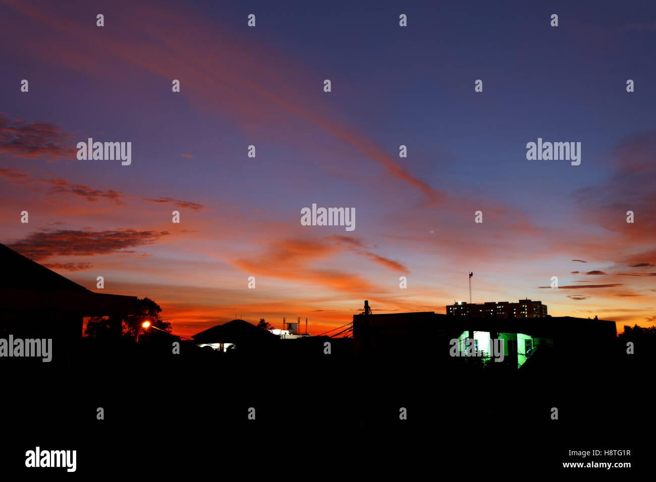 Die rötlichen leuchtenden Wolken am blauen Himmel bei Sonnenuntergang machen sieht die Silhouette des Gebäudes noch schöner. Stockfoto