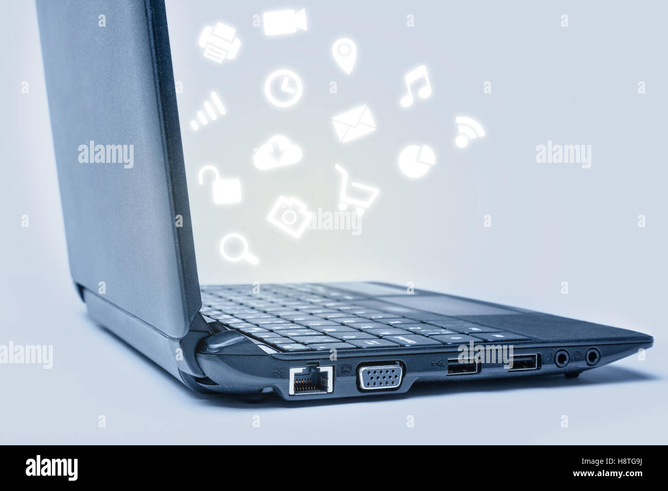 Eine geöffnete Laptop-Tastatur mit gemeinsamen Media-Icons daraus fließt. Stockfoto