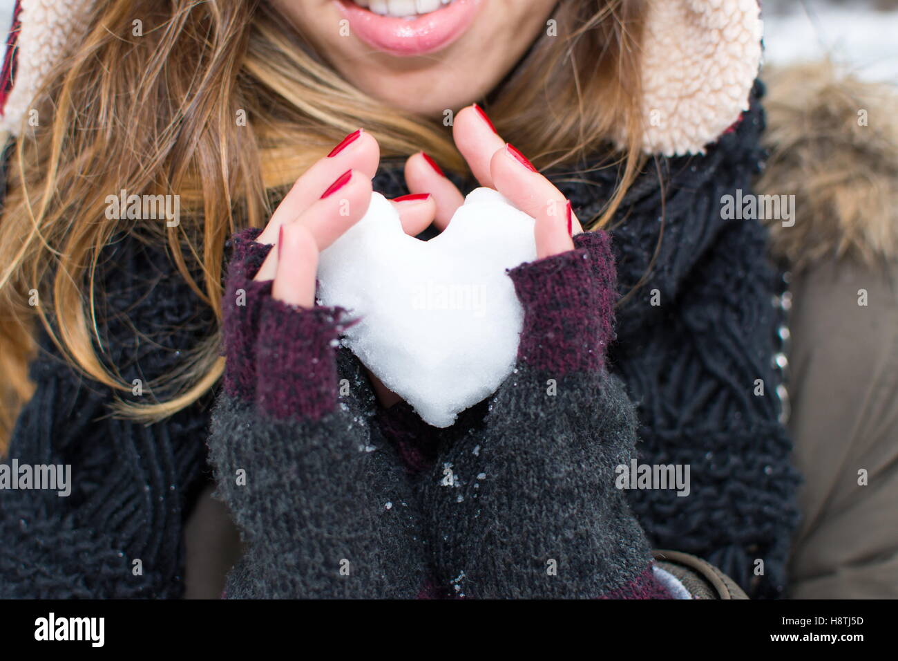 Frau Hände halten Herz geformten Schneeball im freien Stockfoto