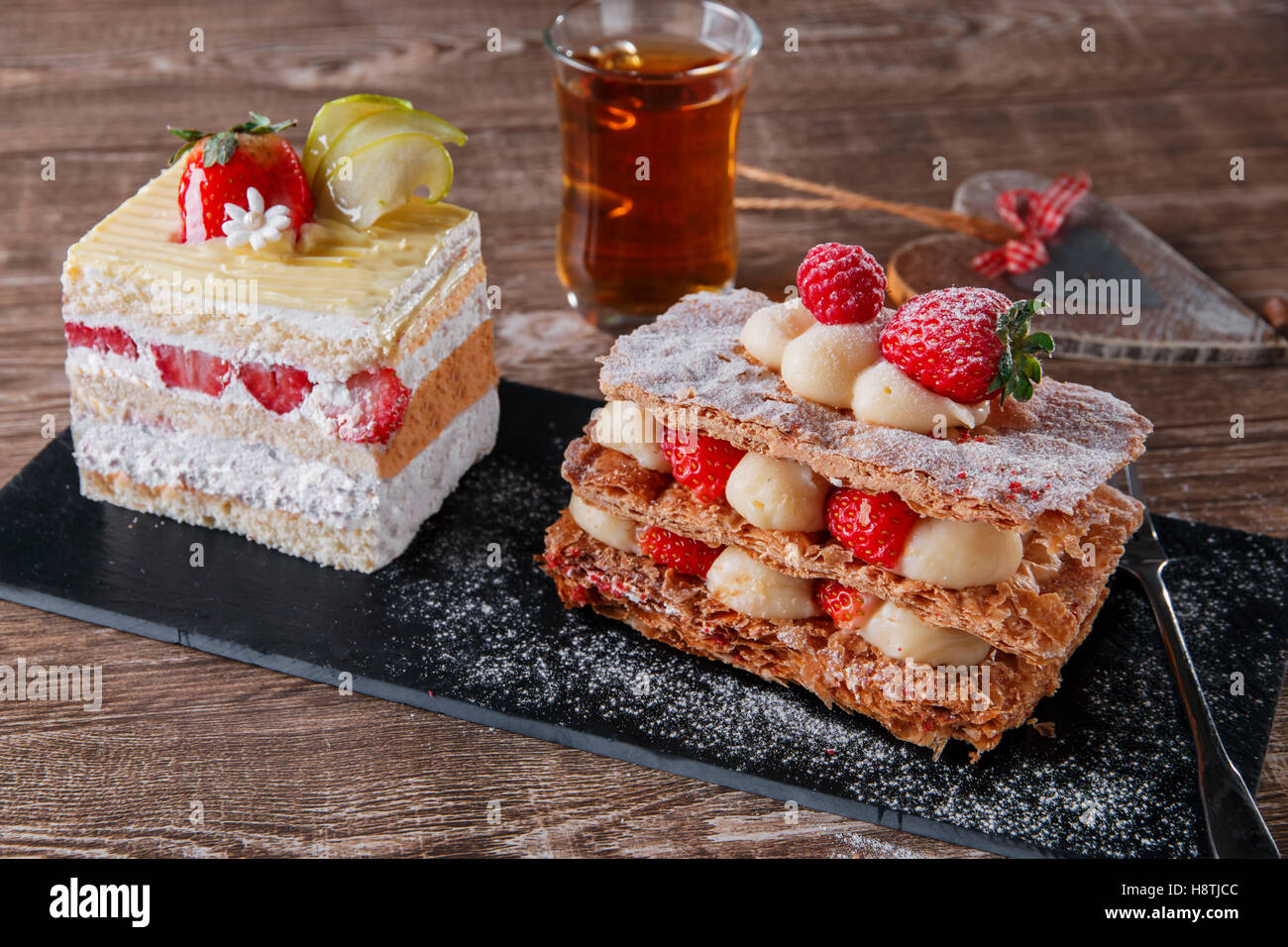 Sahnetorte Erdbeer Glasur Mille Feuille Dessert süß auf schwarzem Stein Stockfoto