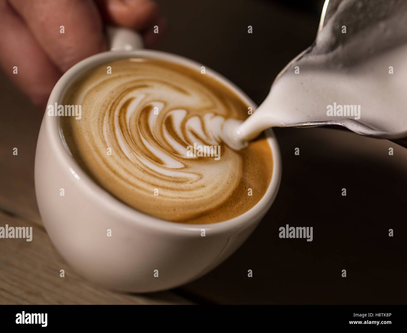 Hand des Barista Latte oder Cappuccino Kaffee gießen Milch Latte Kunst zu machen Stockfoto