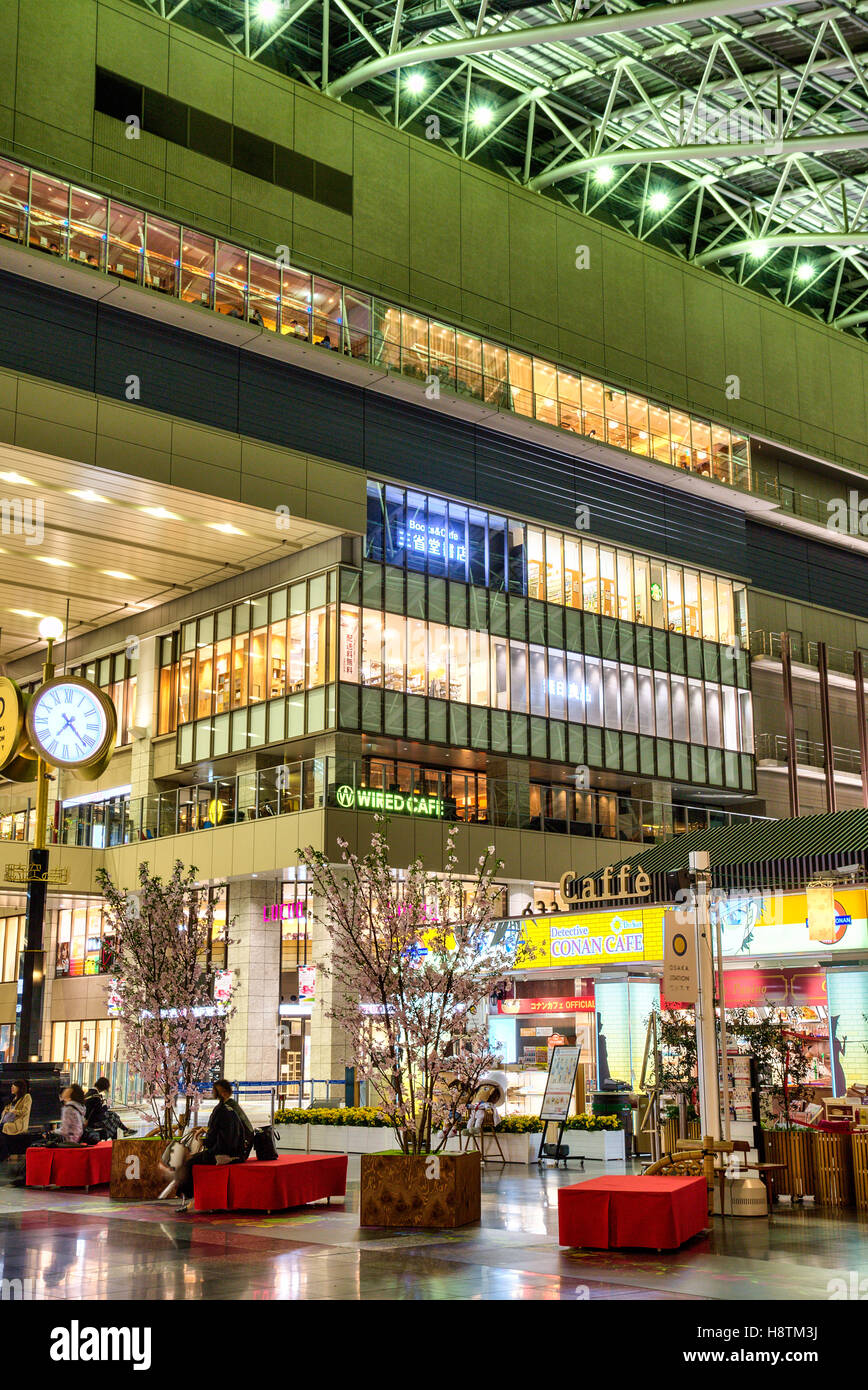 Japan, Osaka Station Stadt Interieur. Taki-no-hiroba PLAZA, mit Uhr, Cafe und North Gate Gebäude Eingangsbereich mit Läden und Geschäfte. Nacht. Stockfoto