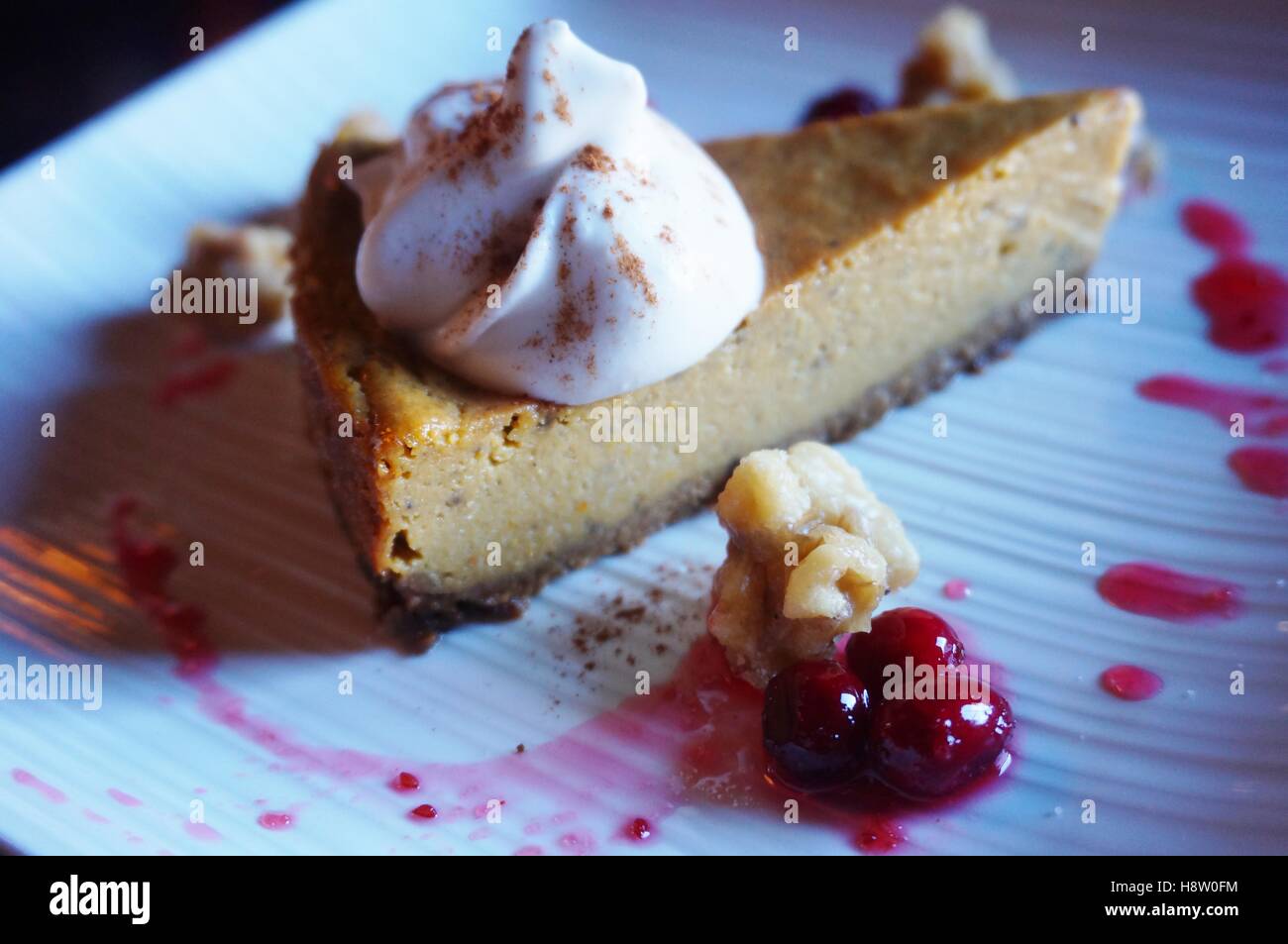 Eine vegane Kürbis-Kuchen Käsekuchen mit Kokos Schlagsahne Sahne und frische Preiselbeeren Stockfoto