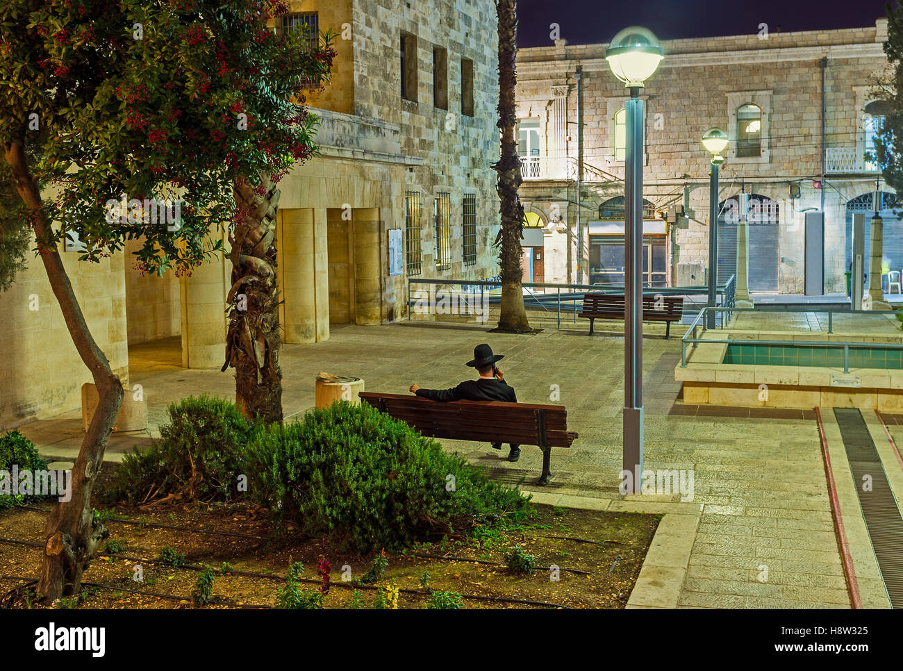 Der Chassid hat das Telefongespräch, sitzen auf der Bank am Abend Daniel Park, Jerusalem, Israel. Stockfoto