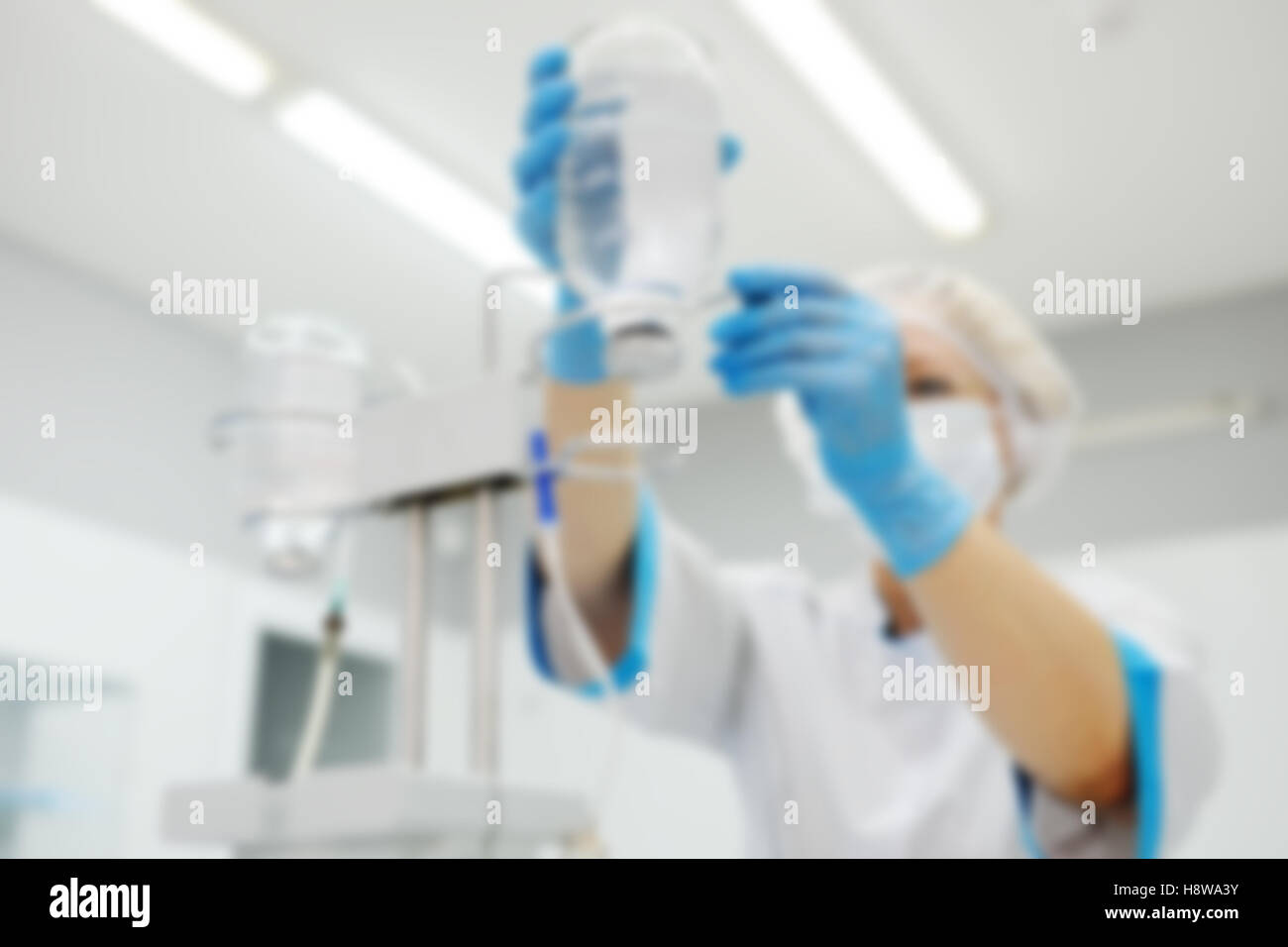 Arzt Frau in medizinischen Maske und sterile Handschuhe, die ein Patient für die Operation vorbereiten. Pipette in eine Vene Nahaufnahme auf einem Hintergrund von Stockfoto