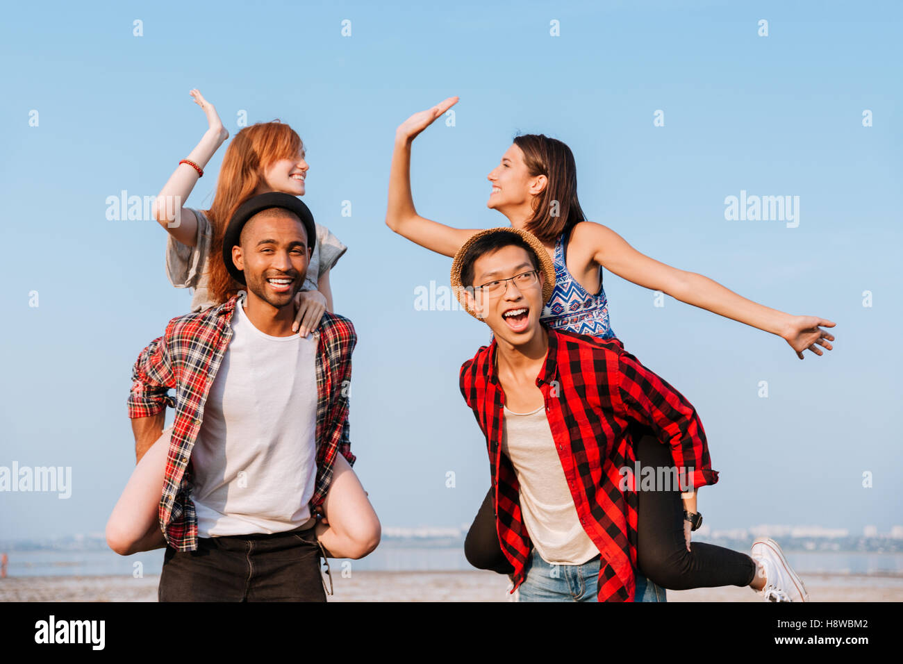 Zwei glückliche junge Paare geben hohe fünf und Spaß im freien Stockfoto