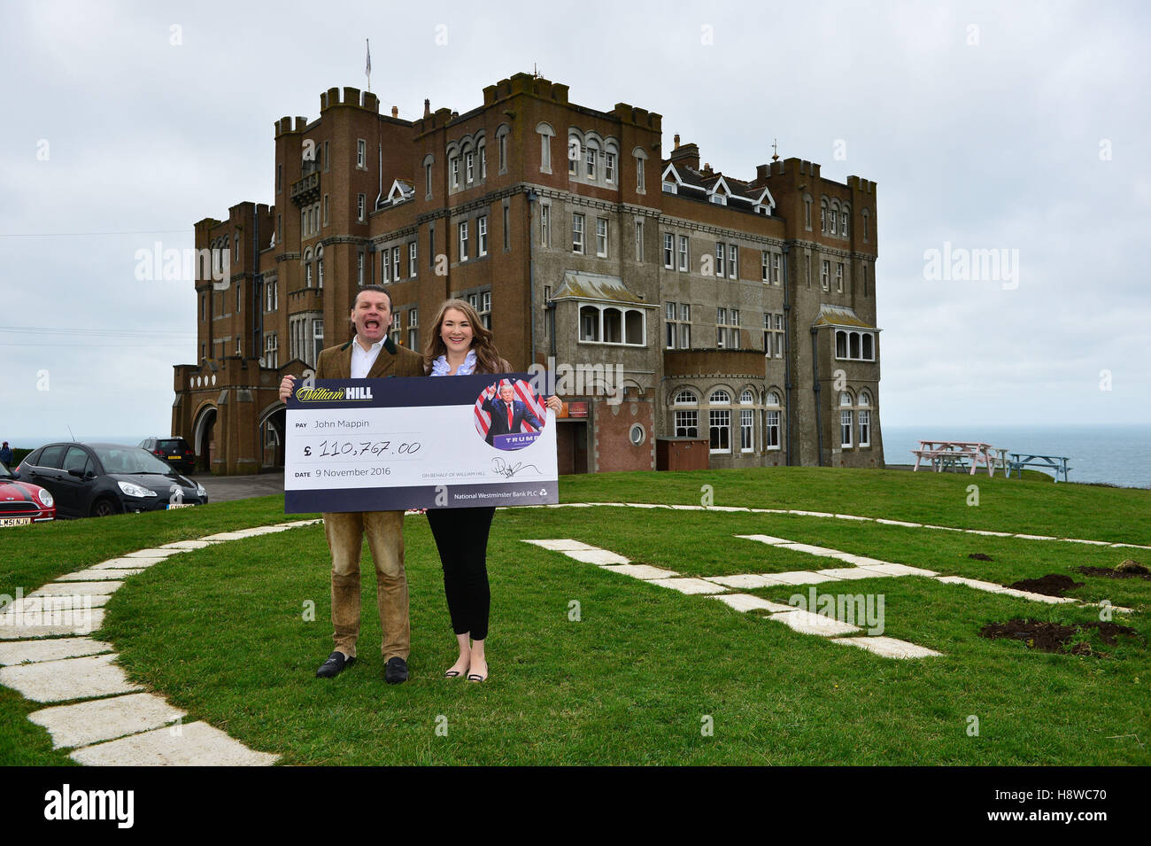 John Mappin, Besitzer von Camelot Castle Hotel in Tintagel, Cornwall, mit seiner Frau Irina und ein Scheck im Wert von £100.000 erhielt er nach dem Platzieren einer Reihe von Wetten auf Donald Trump zum US-Präsidenten von William Hill. Stockfoto