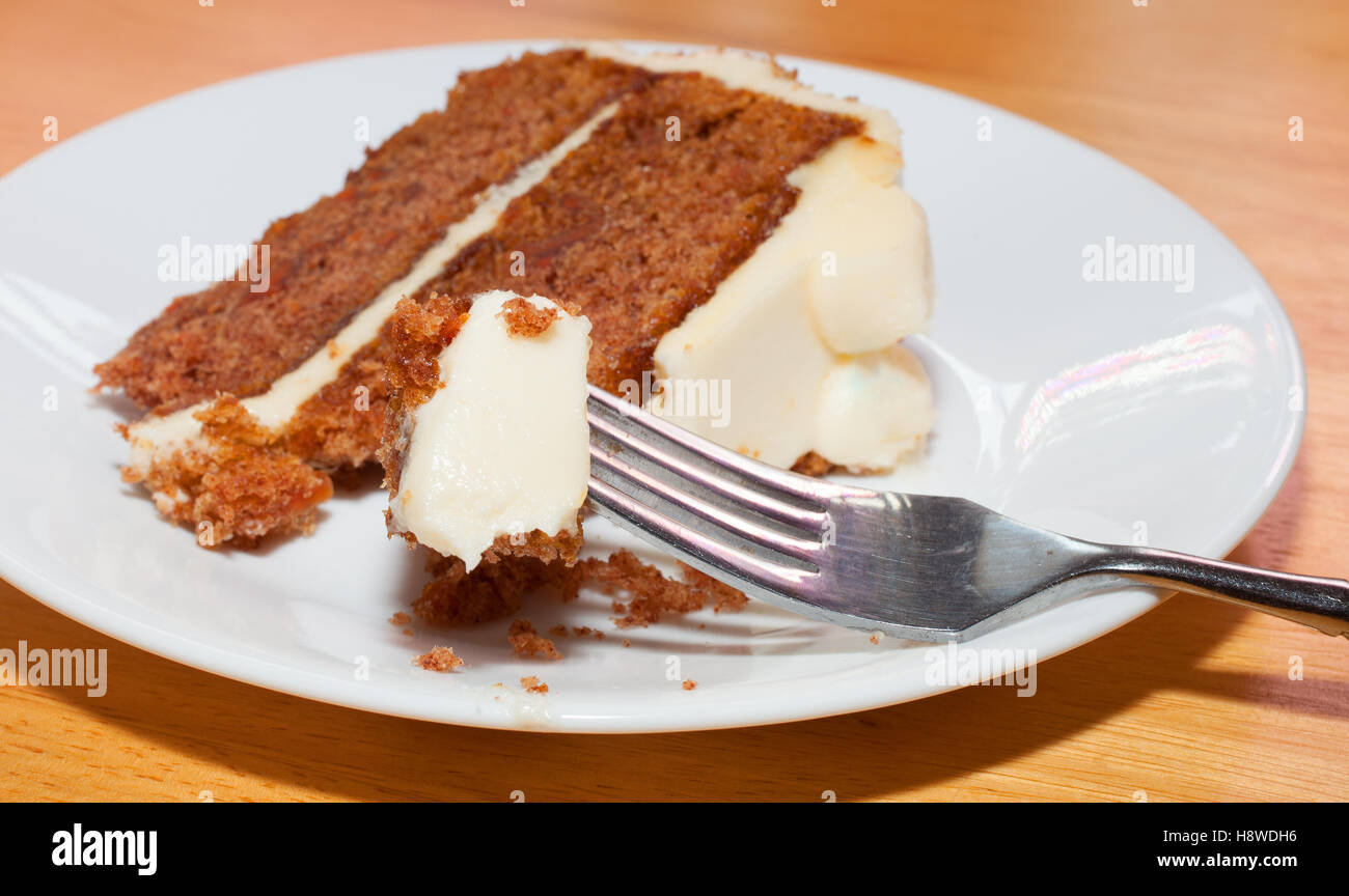 Karotte-Kuchen auf einem Teller mit einer vollen Gabel im Vordergrund Stockfoto