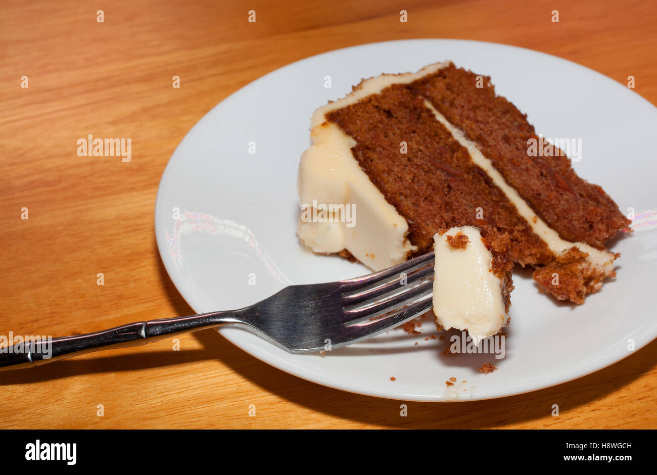 Bissen Karottenkuchen auf einer Gabel mit einem Stück hinter Stockfoto