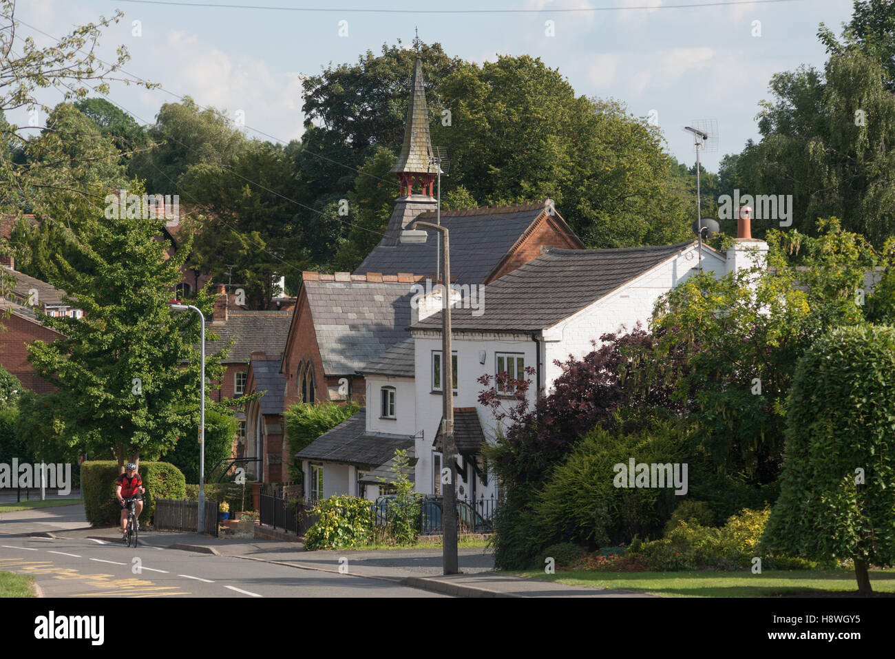 Eine Ferne Radfahrer Fahrrad durch das Dorf Snitterfield, Warwickshire, England, UK Stockfoto