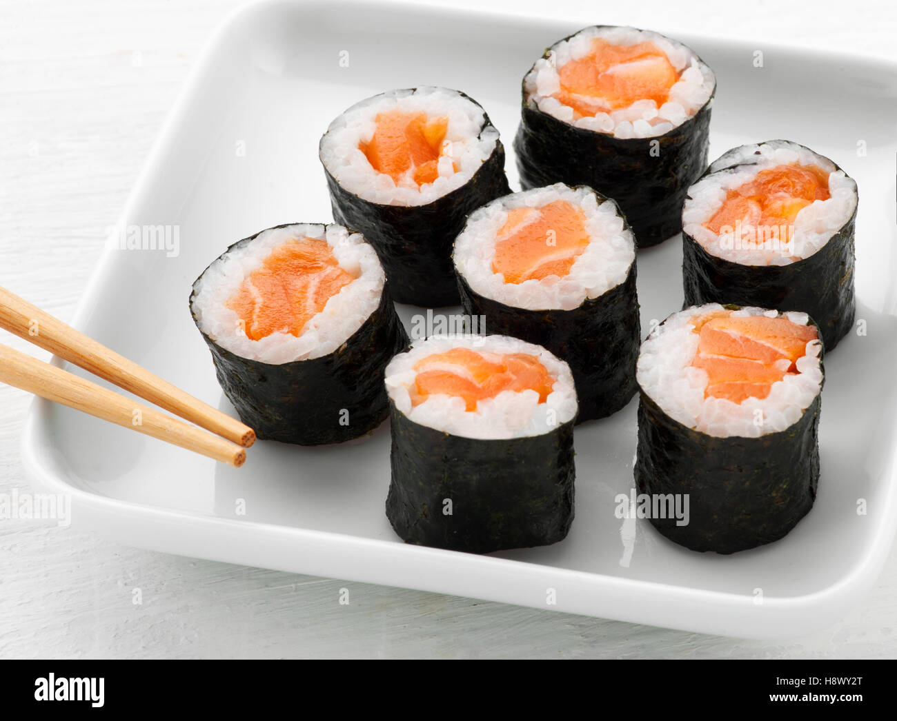 Ausschank von sieben Kombu Lachs Sushi im Sushi-Bar auf einen Teller mit Stäbchen in eine Nahaufnahme hohen Winkel angeordnet Stockfoto