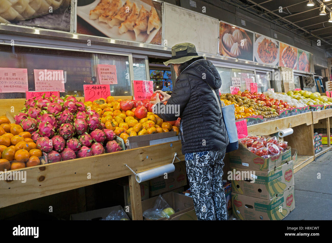 Eine Frau shopping für Obst bei Happy Foods auf Mann Straße & 49. Straße in Chinatown, Flushing, Queens, New York Stockfoto