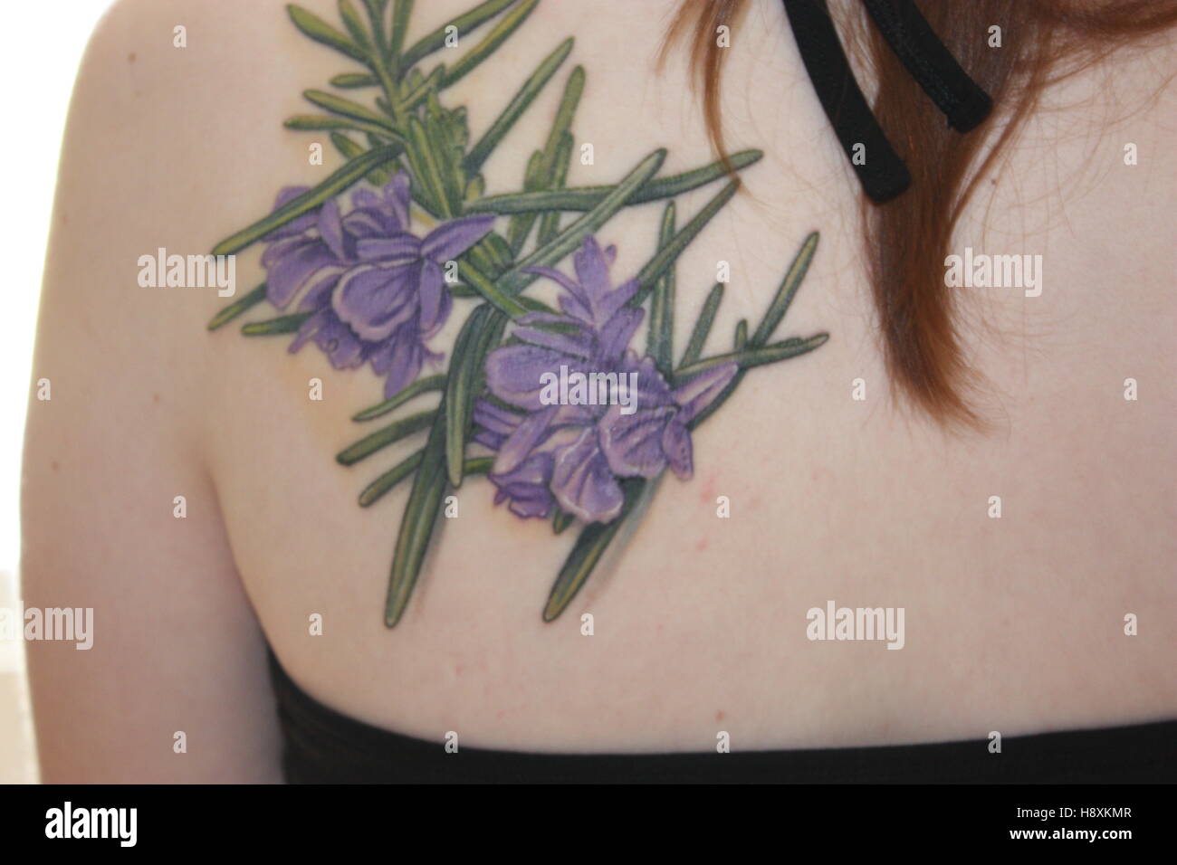 Rosemary Farbe Blume Tattoo auf dem oberen Rücken Halfter Hals Top brünette Haare Stockfoto
