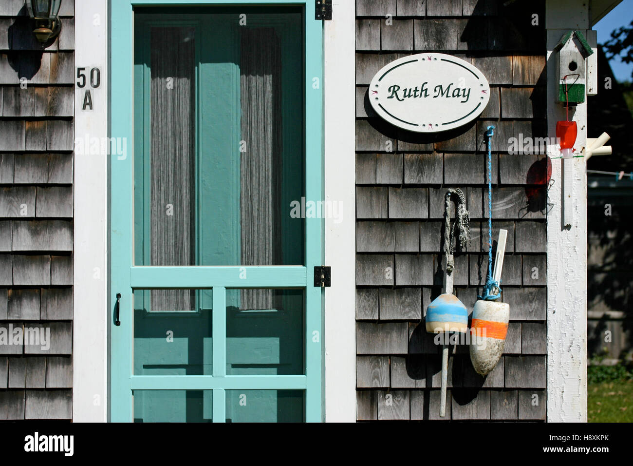 Nahaufnahme eines rustikalen Cape Cod Ferienhauses mit türkisfarbener Tür und grau verwitterten Gürtelrose Stockfoto