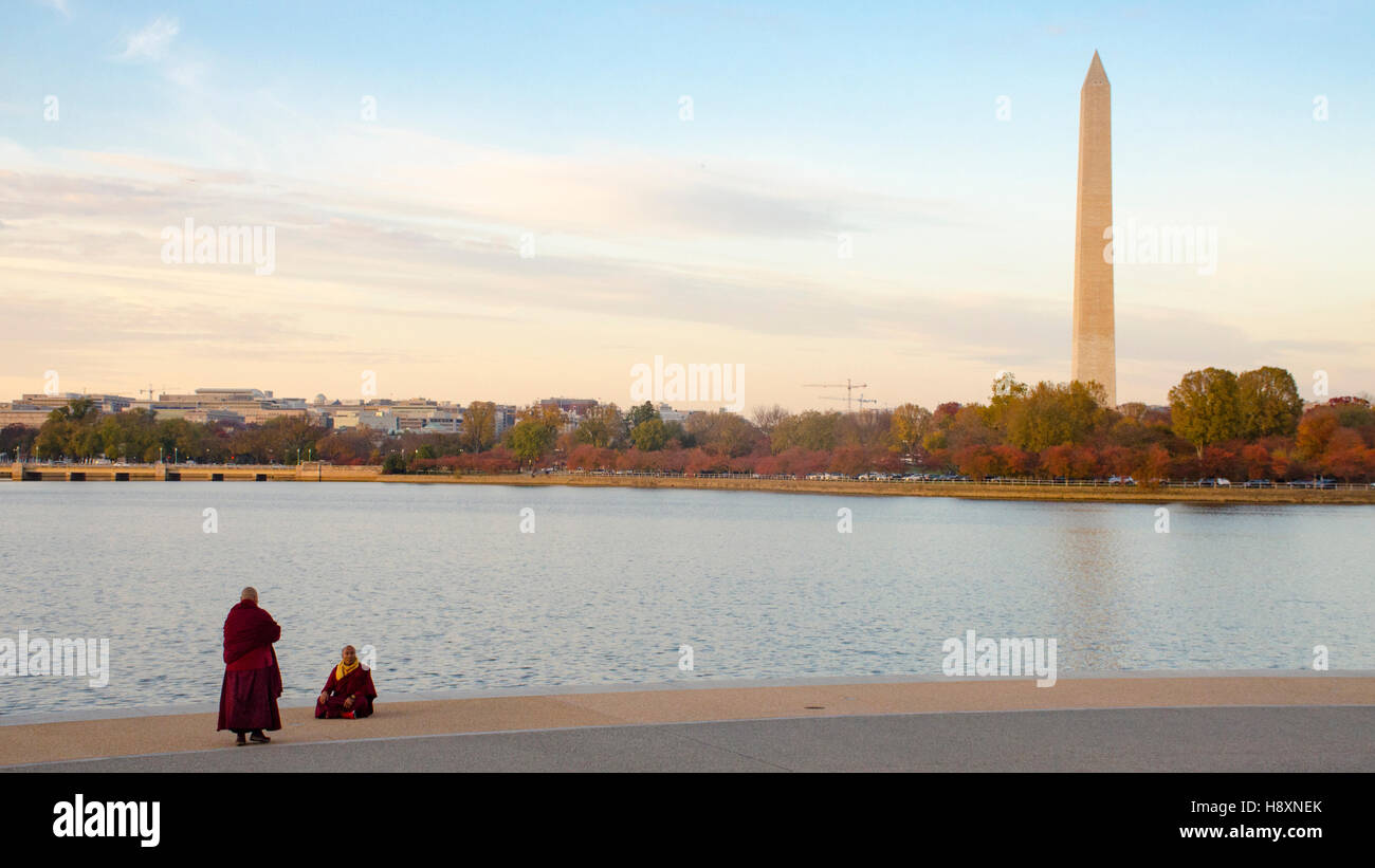 Rot gekleideten Mönche pause für Fotos an den Ufern des Tidal Basin in Washington DC. Washington Monument ist auf der rechten Seite. Stockfoto