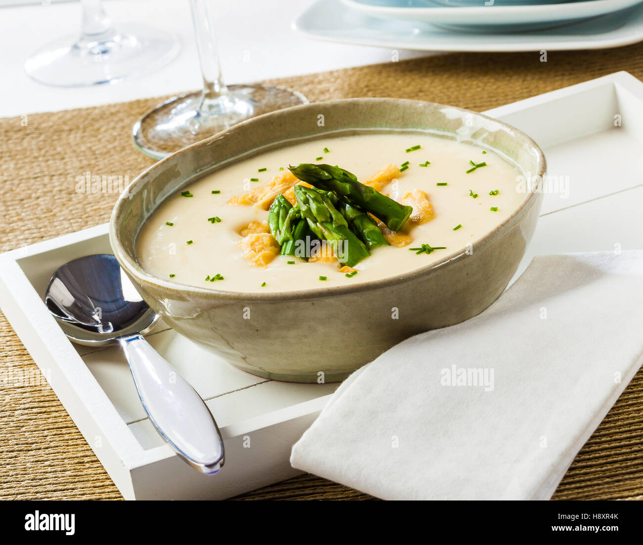 Spargel-Creme-Suppe mit Huhn in einer Schüssel auf einem weißen Tablett. Stockfoto