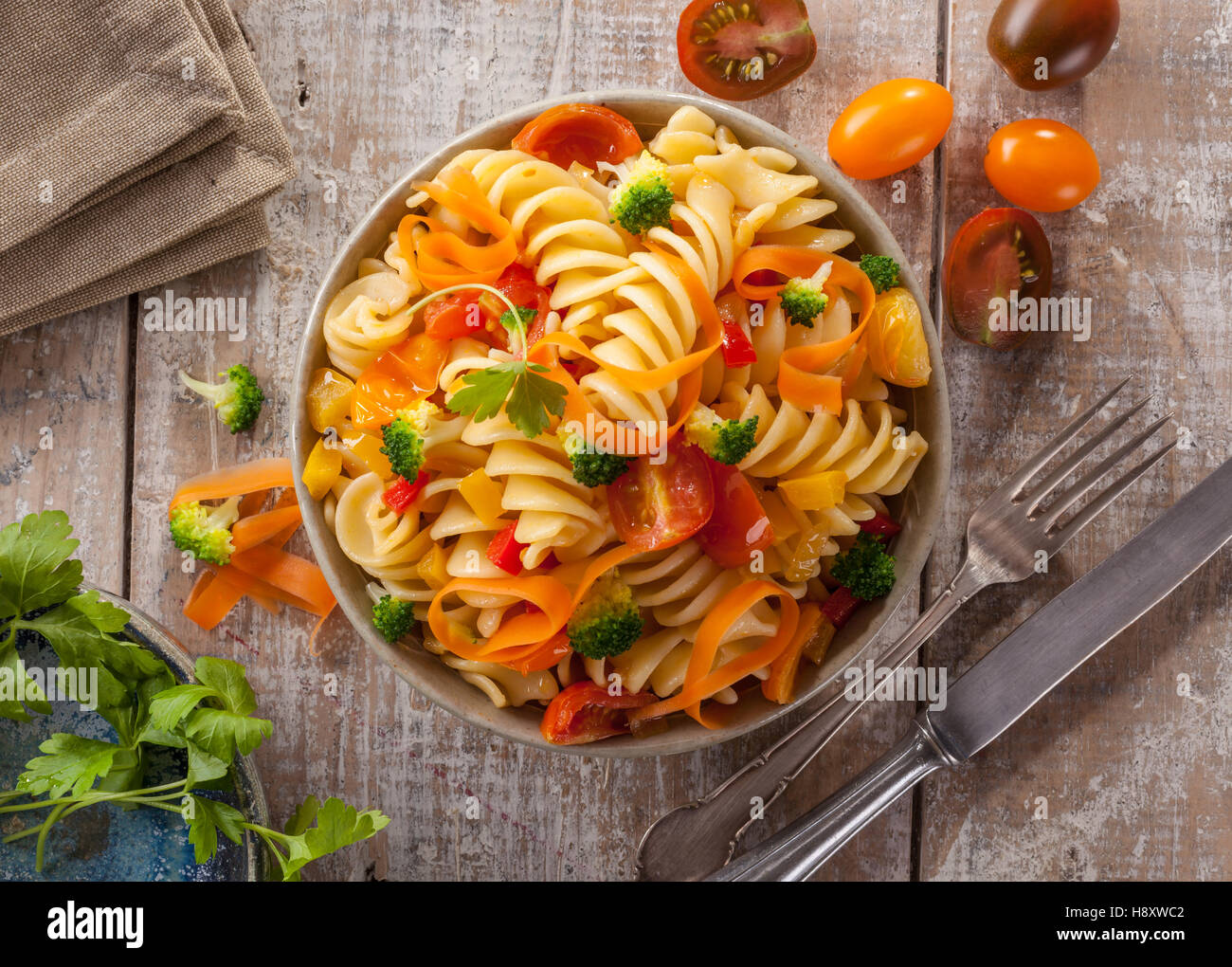 Fusilli Nudeln mit bunten Tomaten, Karotten und Brokkoli auf einem weißen Holztisch italienische Küche. Stockfoto