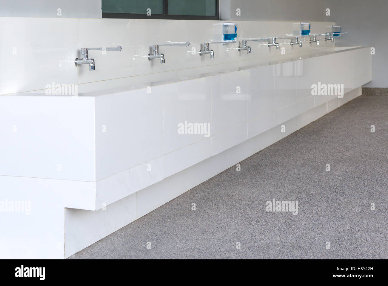 Lange Reihe von fließendem Wasser und Waschbecken in der Schule. Stockfoto