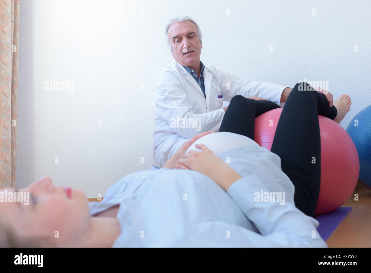 Arzt mit der schwangeren Frau mit Gymnastik ball Stockfoto