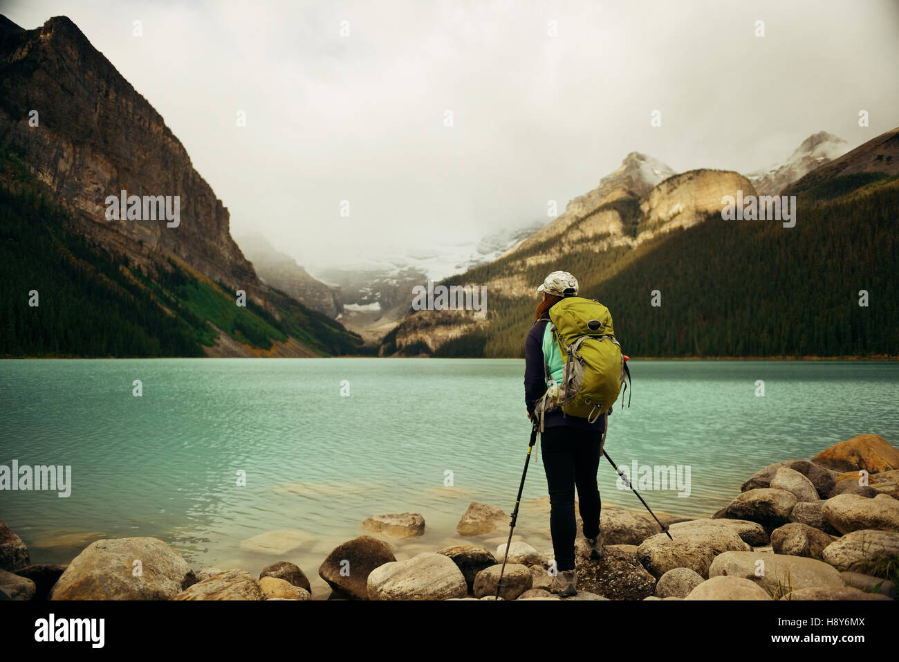 Eine weibliche Wanderer am Lake Louise im Banff Nationalpark mit Bergen und Wäldern in Kanada. Stockfoto