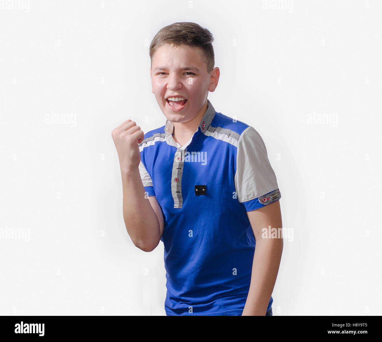 Teenager genießt Erfolg, viel Glück. Der Mann im blauen Hemd auf weißem Hintergrund Stockfoto