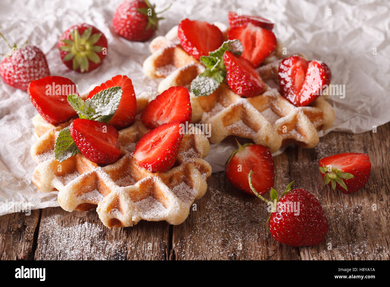 Schöne süße Waffeln mit Erdbeeren, Puderzucker und Minze-close-up auf dem Tisch. horizontale Stockfoto