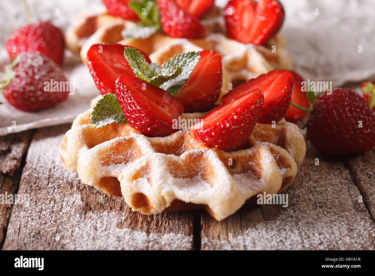 Belgische Waffeln mit Erdbeeren und Puderzucker Nahaufnahme auf dem Tisch. horizontal, Makro Stockfoto