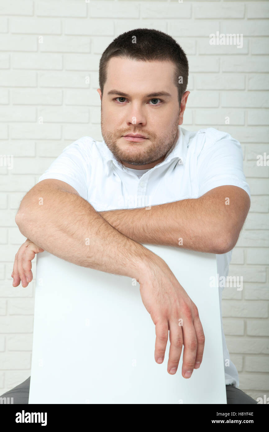 Mann mittleren Alters mit gepflegten Bart, beim Sitzen in der Nähe der Wand in die Kamera schaut. Stockfoto