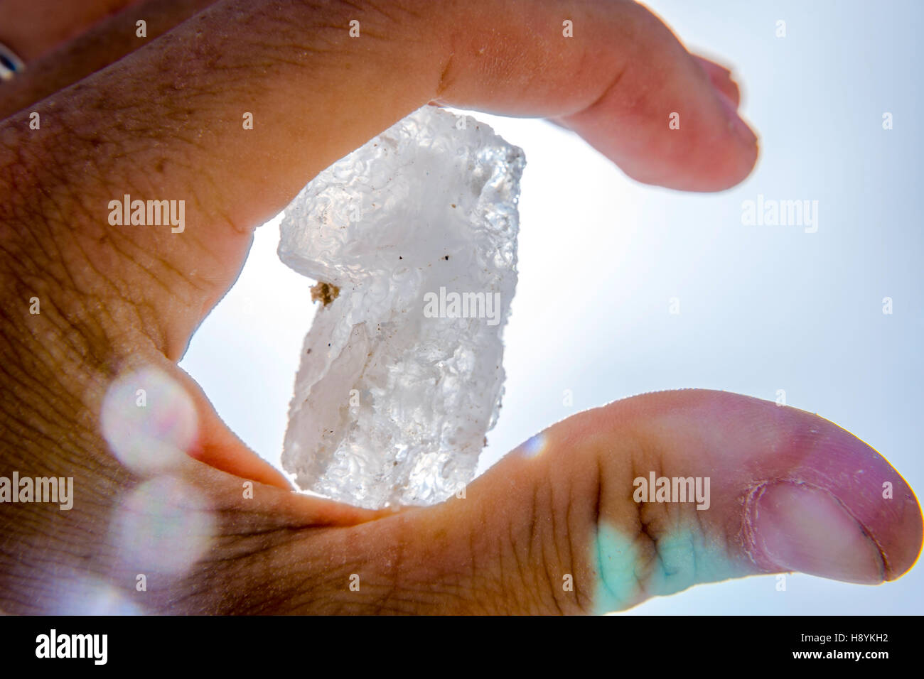 Halten große Salzkristall in der hand gegen blauen Himmel Stockfoto