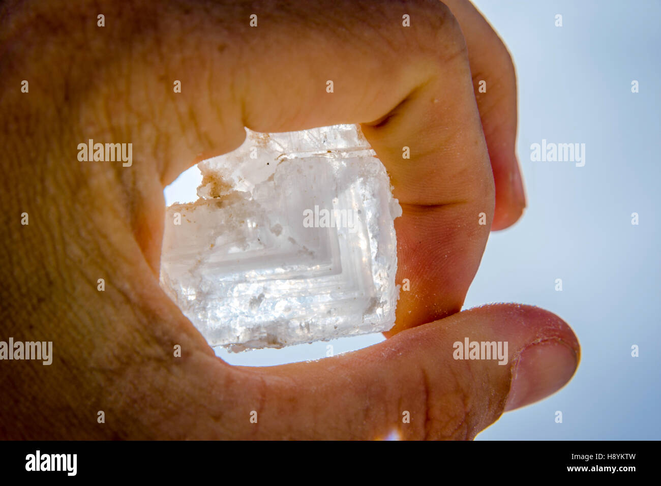 Halten große Salzkristall in der hand gegen blauen Himmel Stockfoto