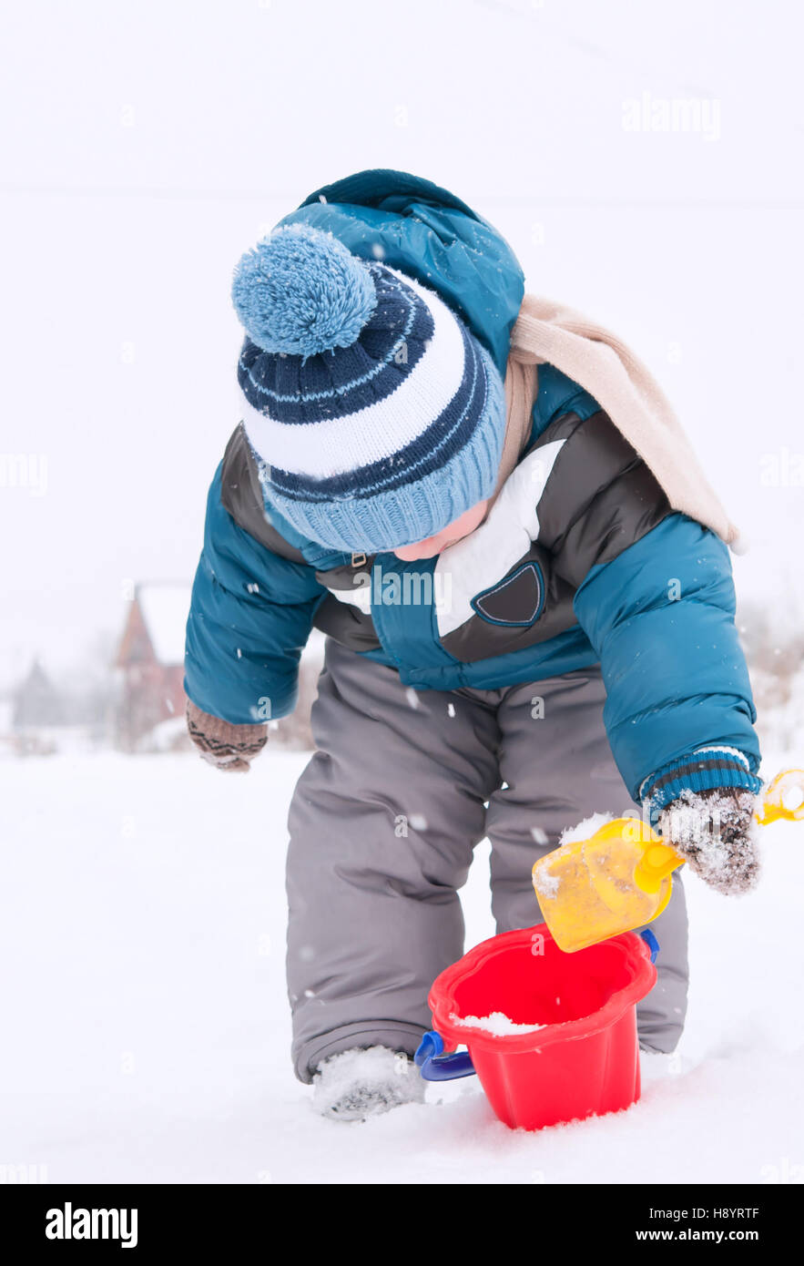 glückliches kleines Kind spielt im Schnee Stockfoto