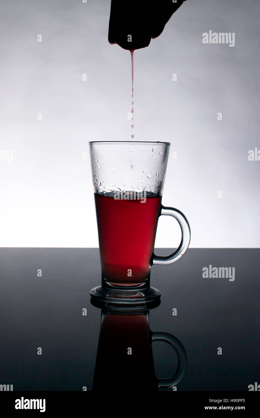In der Nähe von kommerziellen Rote Früchte Tee Beutel getaucht In kristallklarem Glas Wasser Stockfoto
