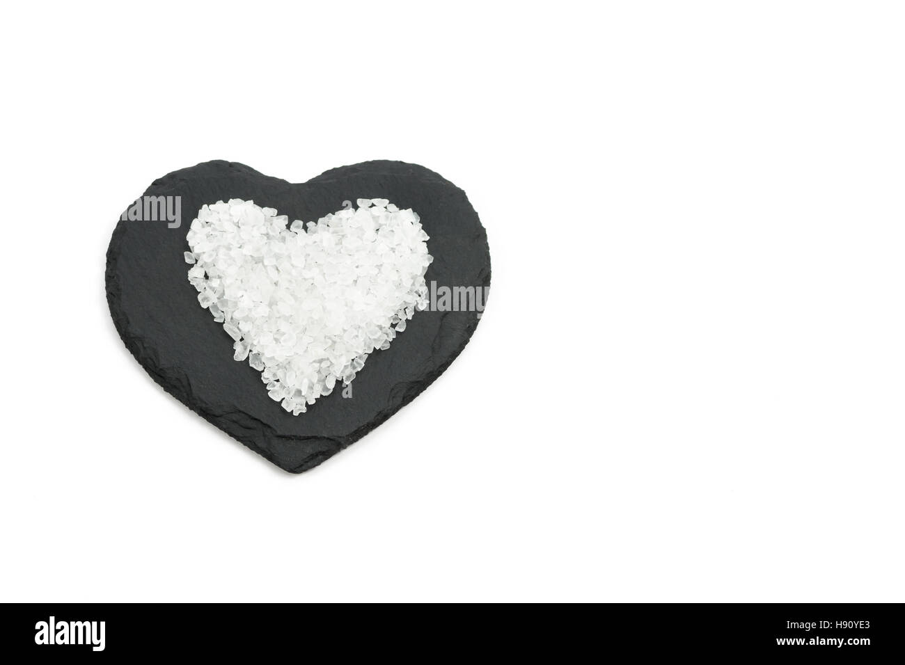 Steinsalz-Herzen auf schwarzem Schiefer Herzform Stockfoto