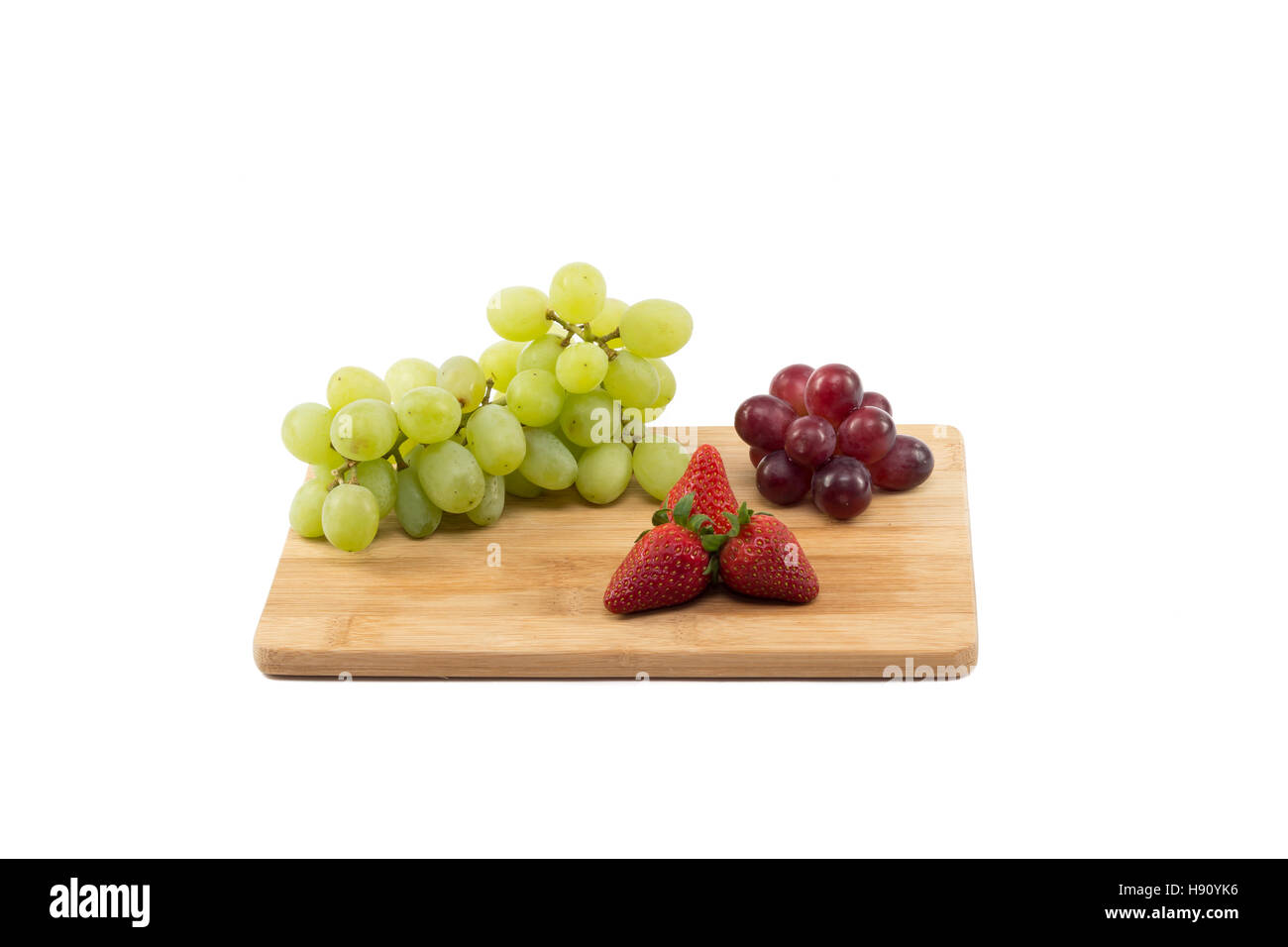 Rote und grüne Trauben und Erdbeeren auf Holzbrett isoliert auf weißem Hintergrund Stockfoto
