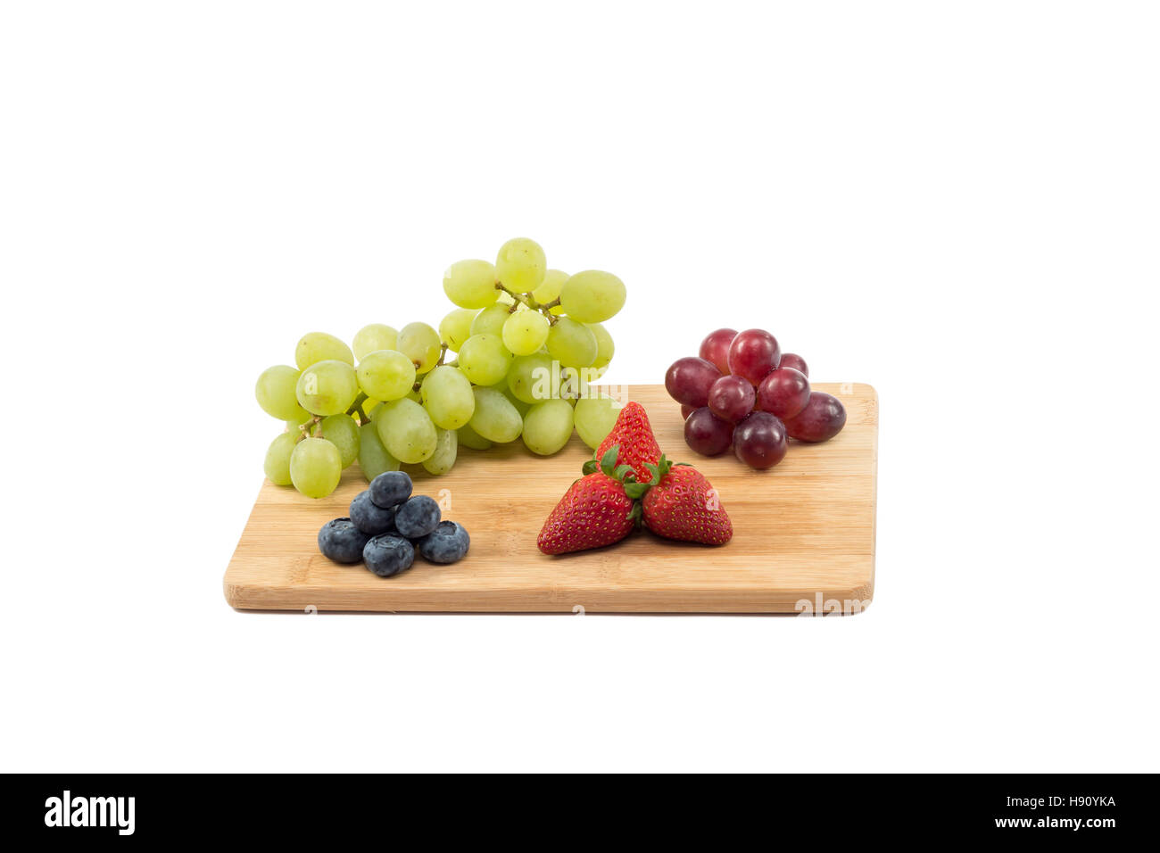 Rote und grüne Trauben, Erdbeeren und Heidelbeeren auf einem Holzbrett isoliert auf weißem Hintergrund Stockfoto