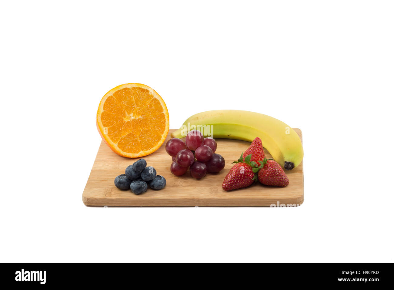 Rote Trauben mit einer halben Orange, Erdbeeren, Blaubeeren und Bananen auf Holzbrett isoliert auf weißem Hintergrund Stockfoto