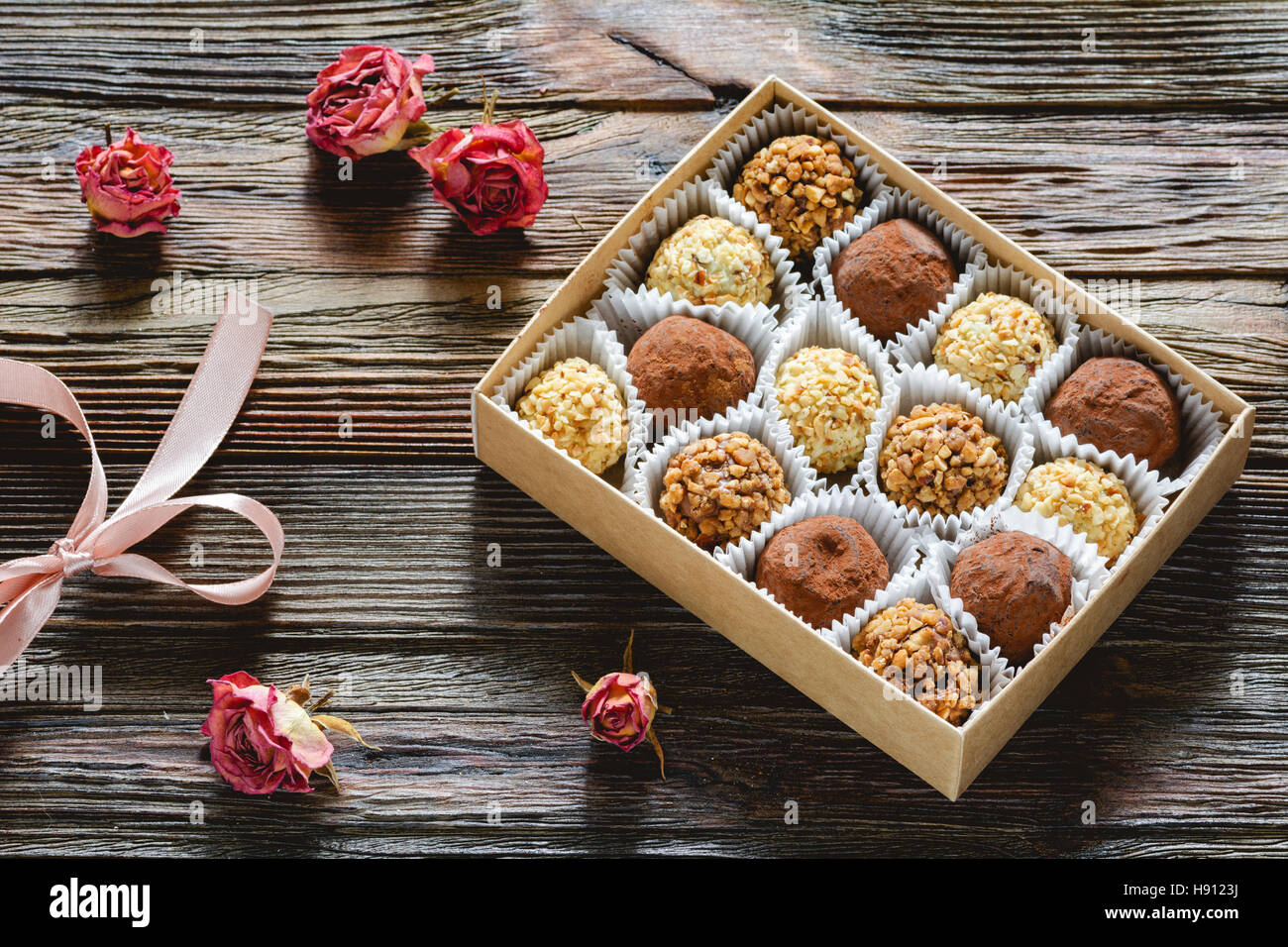 Box mit köstlichen Schokoladen und Pralinen und getrocknete rosa Rosen. Valentinstag Geschenk, Valentine Tag Konzept Stockfoto