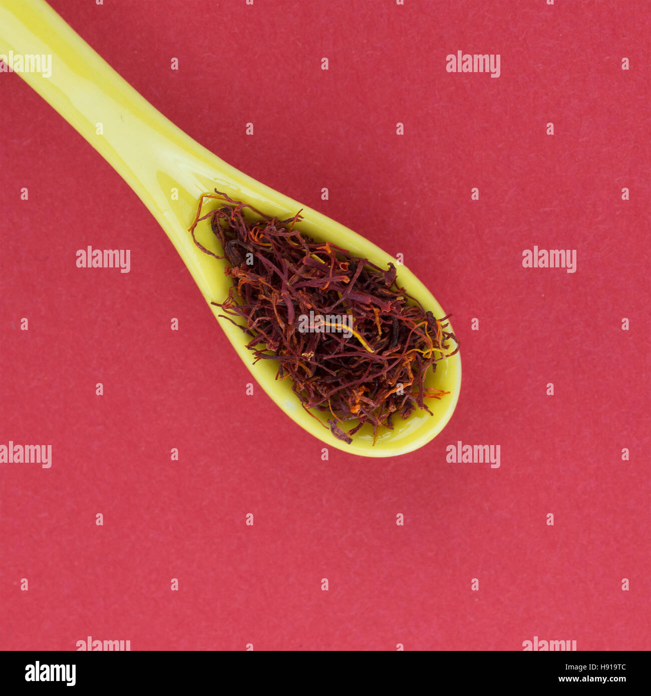 Safran auf einem gelben Löffel erschossen auf einem roten Hintergrund in ein quadratisches Format von oben Stockfoto Safran auf einem gelben Löffel erschossen auf einem roten Hintergrund in ein quadratisches Format von oben Stockfoto