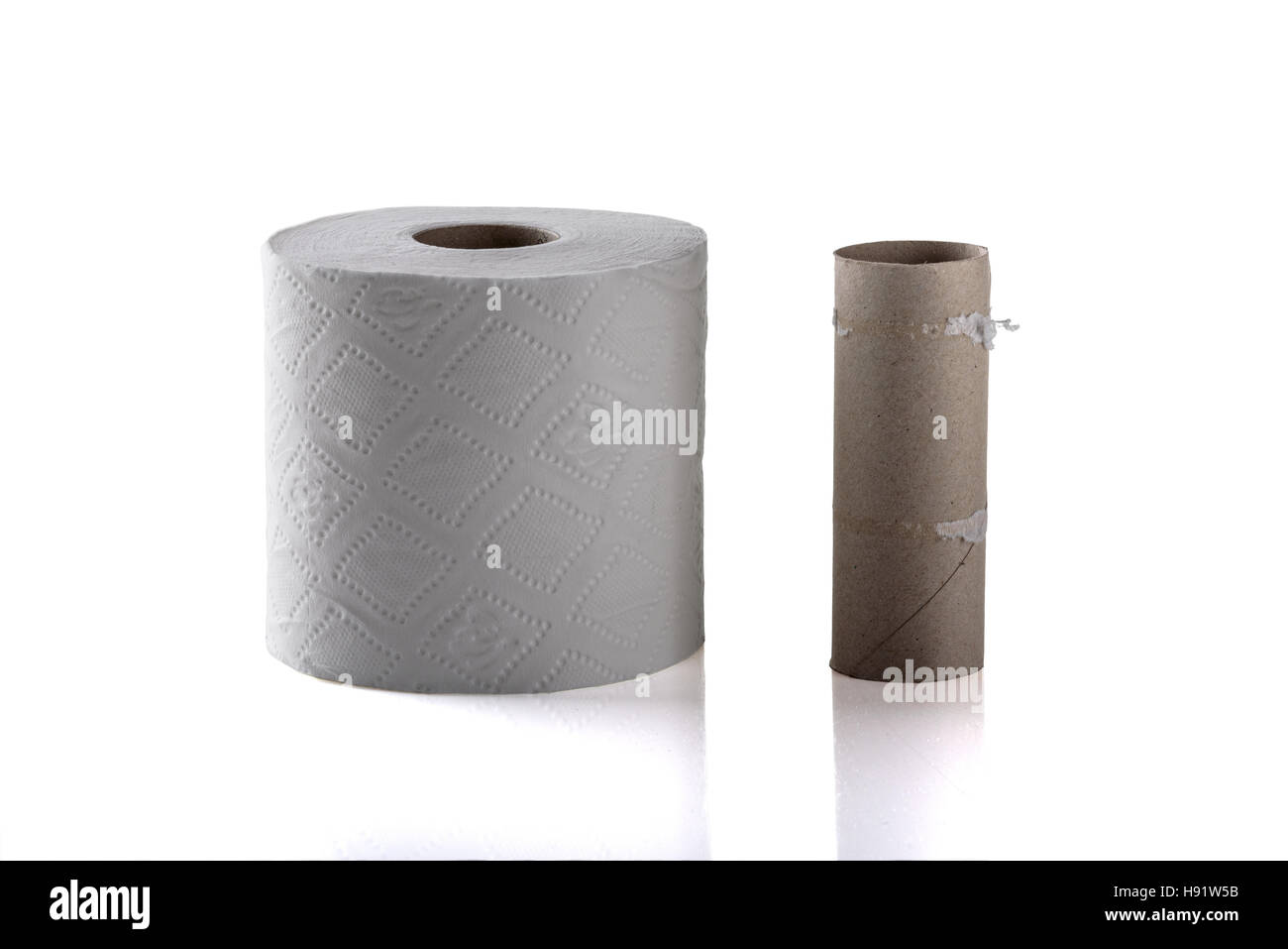Einzelne leere Toilettenpapierrolle neben eine neue volle Rolle. Stockfoto