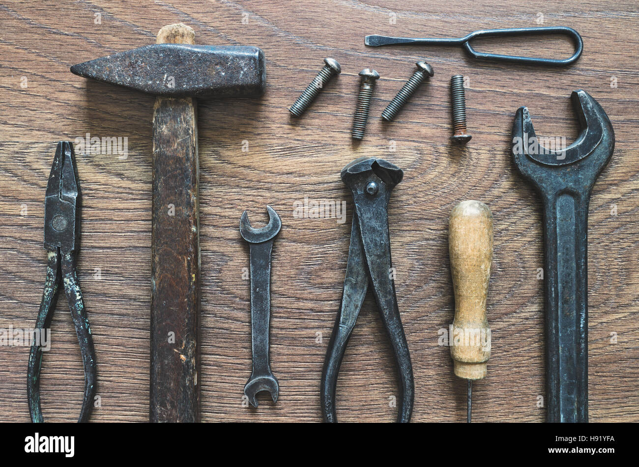 Verschiedene Werkzeuge (Zange, Hammer, Ahle, Schraubenschlüssel, Zangen, Meißel) auf einem hölzernen Hintergrund. Stockfoto