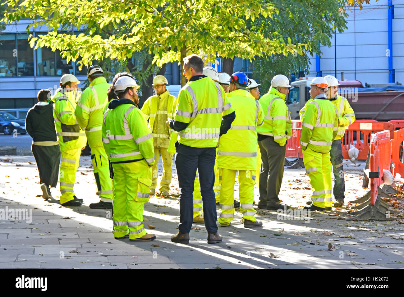 Group Manager Aufsichtsbehörden Ingenieure Vorarbeiter Vermesser treffen neben dem großen Baustellen-Projekt-Firmen-Logos entfernt London England UK Stockfoto