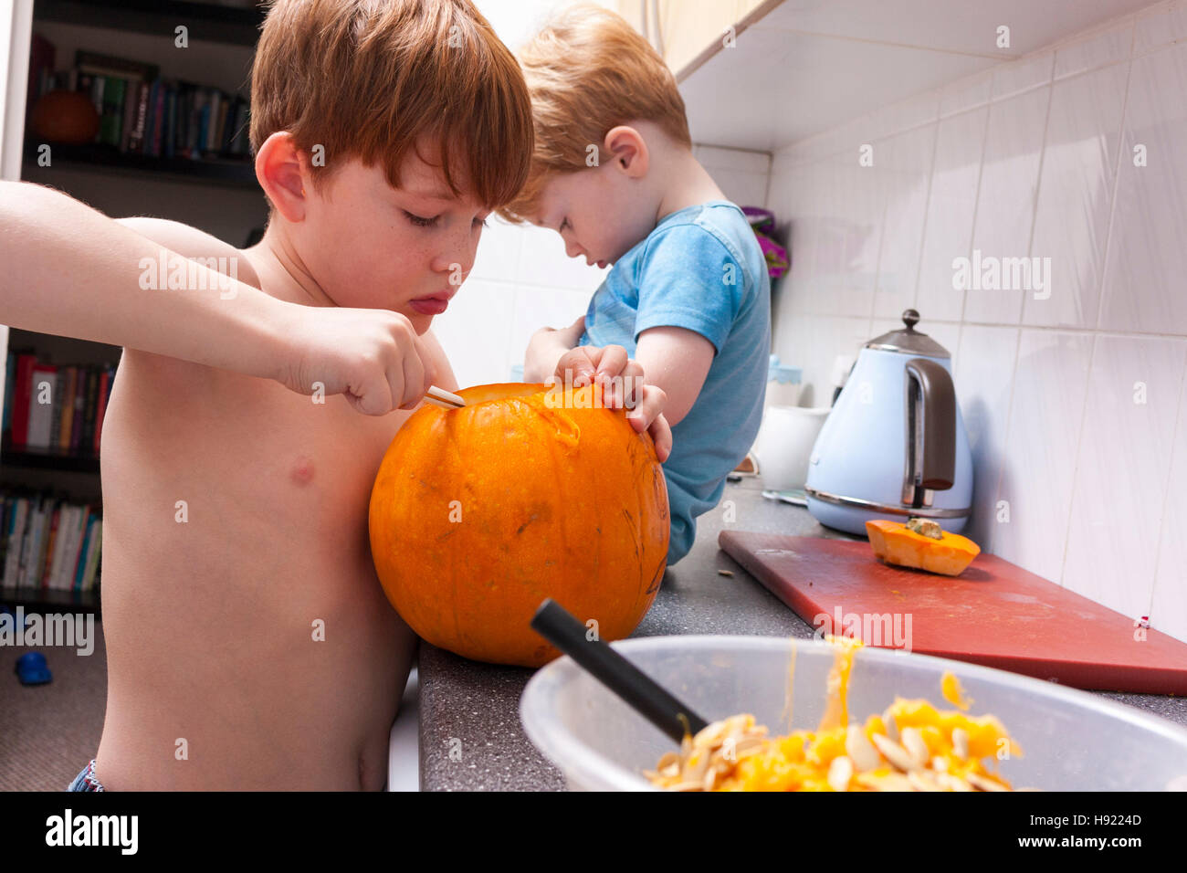 Kaukasische junge carving einen Kürbis für Halloween in einer Küche Stockfoto