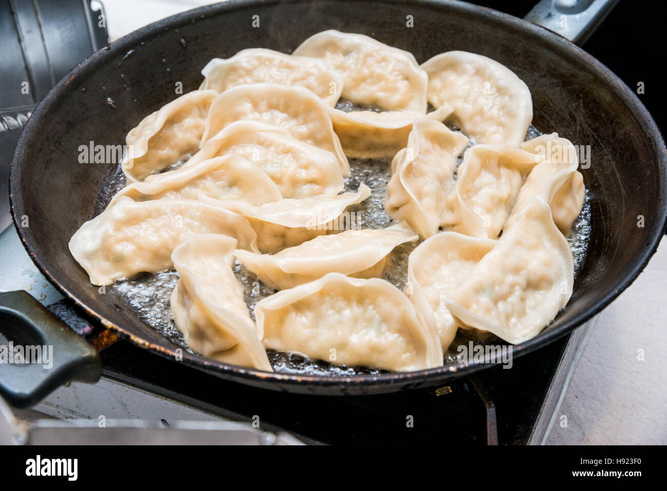 Chinesische Knödel kochen in Gusseisen Pfanne Stockfoto