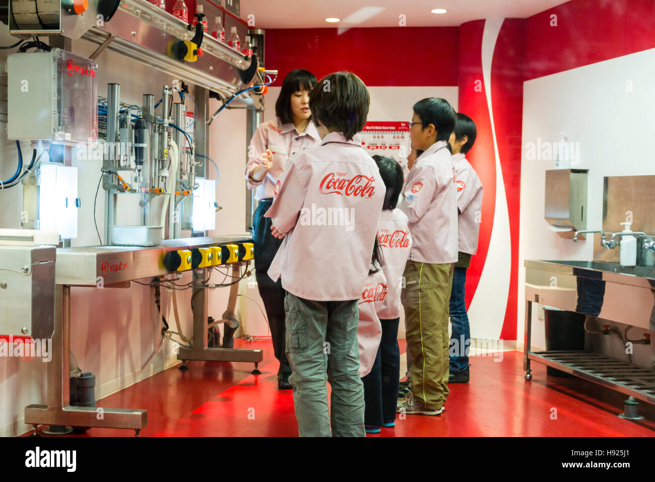 Japan, Nishinomiya, KidZania, Indoor Kinder Aktivität spielen Park. Coke-Cola Abfüllanlage, japanische Frauen Lehre 4 Kinder wie Maschine zu verwenden. Stockfoto