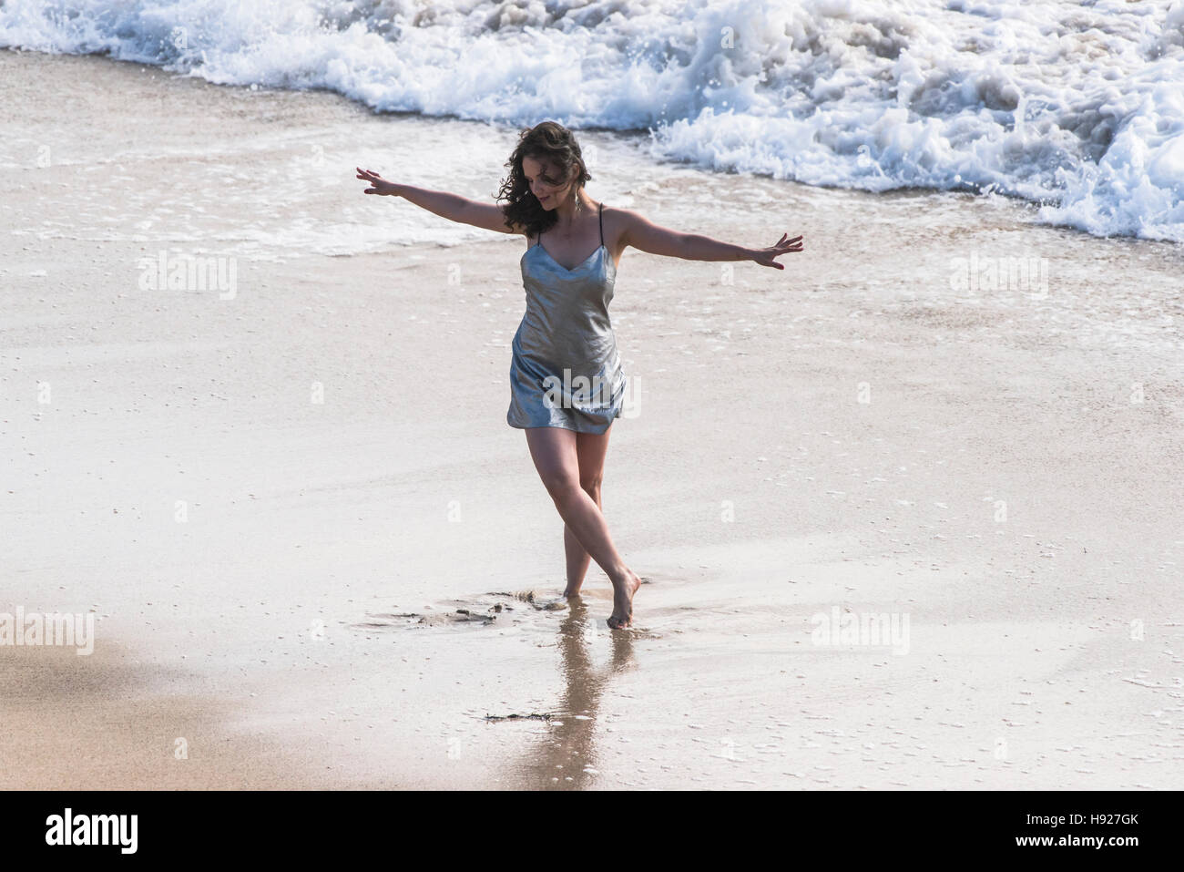 Eine Frau tanzt am Fistral Strand in Newquay in Cornwall. Stockfoto