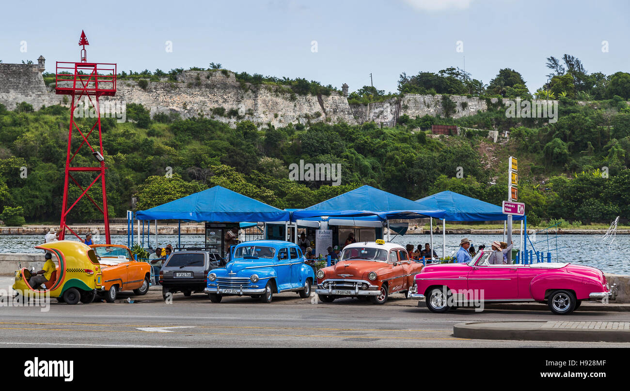 Vier wunderschön farbigen klassische Autos aus den 50er Jahren warten Sie auf der Seite der Malecon Ozean Autobahn in Havanna. Stockfoto