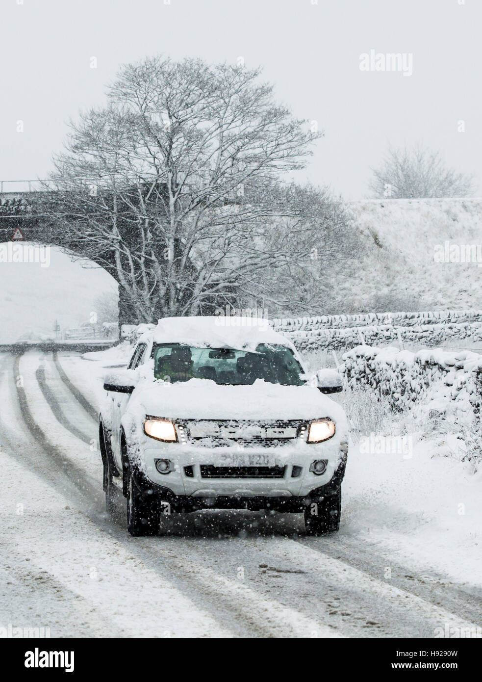 Ein Auto auf der Straße zwischen Ingleton und Hawes in den Yorkshire Dales National Park nach Winterwetter Schnee auf einer Anhöhe im Norden von England gebracht. Stockfoto